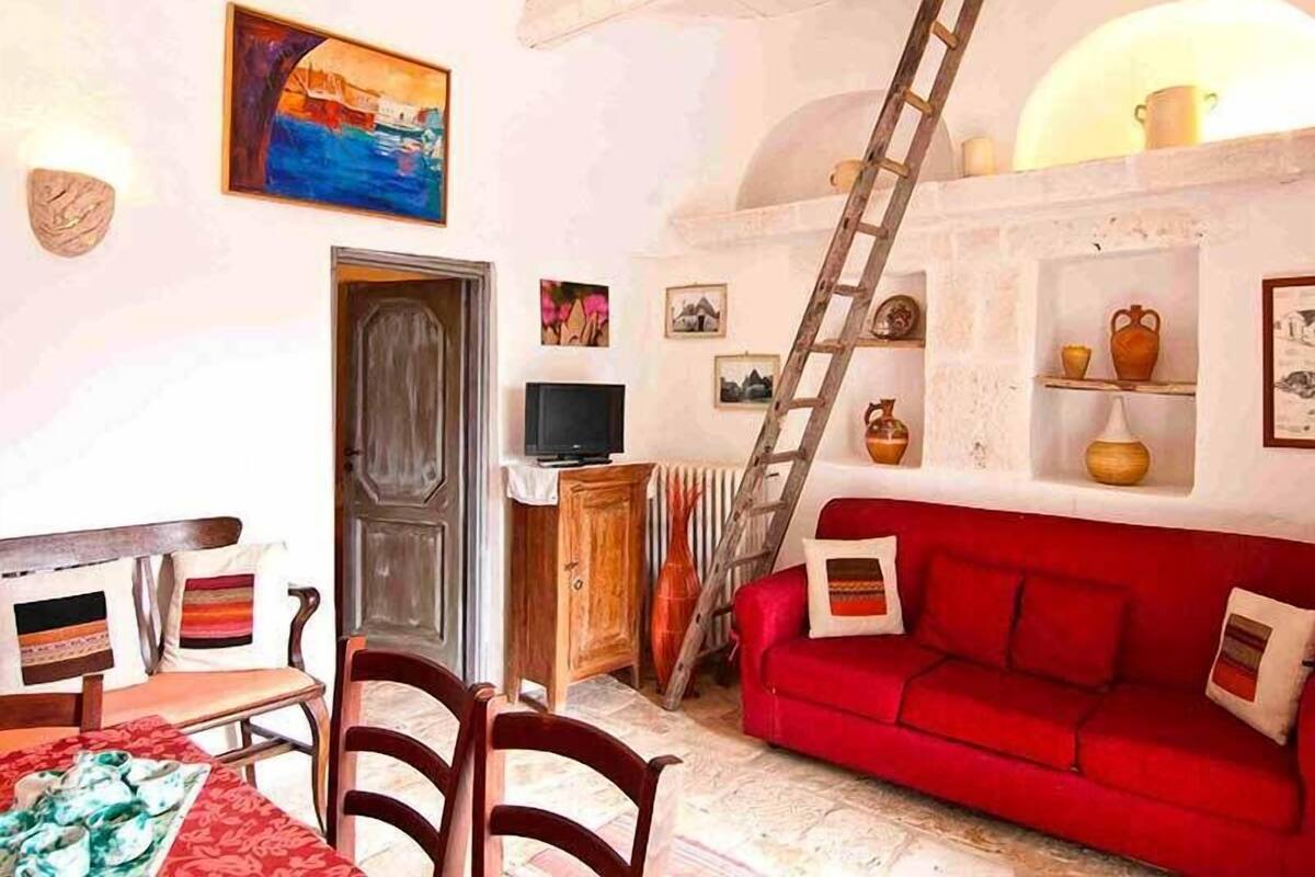 Una habitación acogedora con un sofá rojo, muebles de madera, un televisor y una escalera.