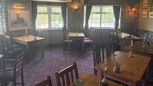 Un coin repas rustique avec des murs en pierre, des tables et des chaises en bois.