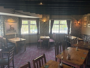 A rustic dining area with stone walls, wooden tables, and chairs. - Hunters Rest Inn (Bristol)