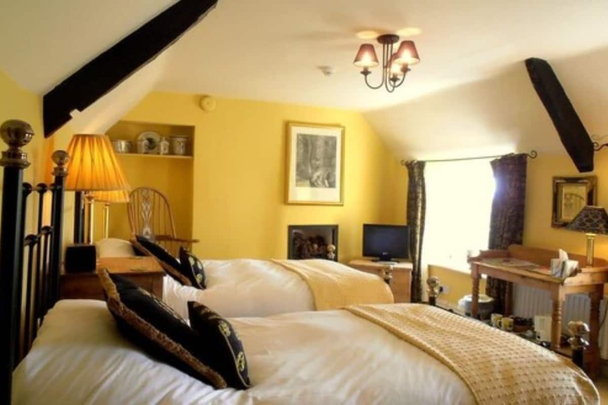 A bedroom with a bed, a desk, a chair, a lamp, and a television.