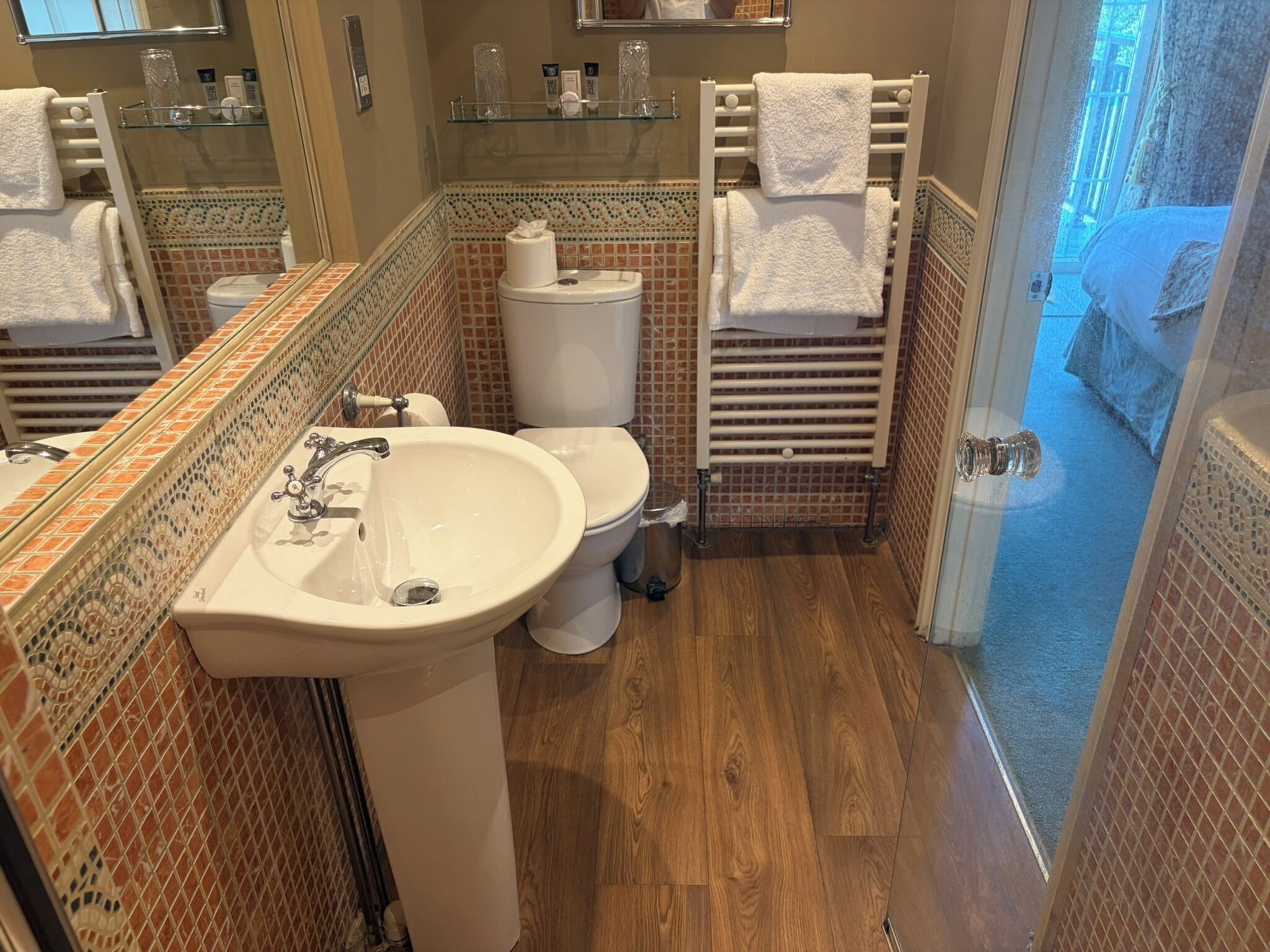 A bathroom with a sink, toilet, and towel racks.