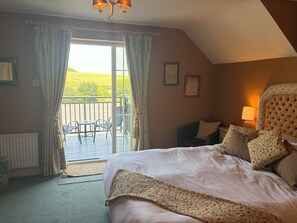 A bedroom with a large bed, a balcony with chairs, and a view of the outdoors. - Hunters Rest Inn (Bristol)