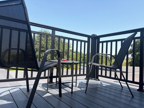 A deck with two chairs and a small table, surrounded by a black railing.