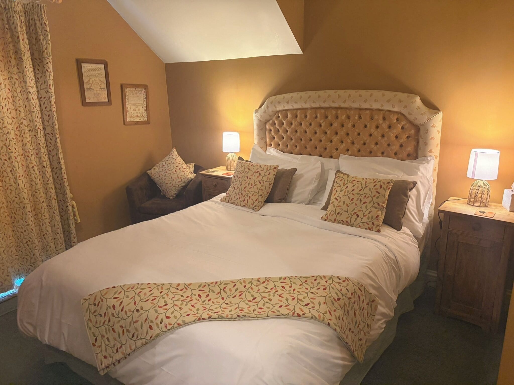 A hotel room with a large bed, two bedside tables with lamps, a chair, and a window with curtains.