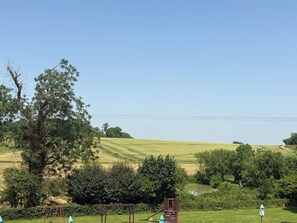 A rural landscape with a clear sky, a field, and a playground with swings and a slide. - Hunters Rest Inn (Bristol)