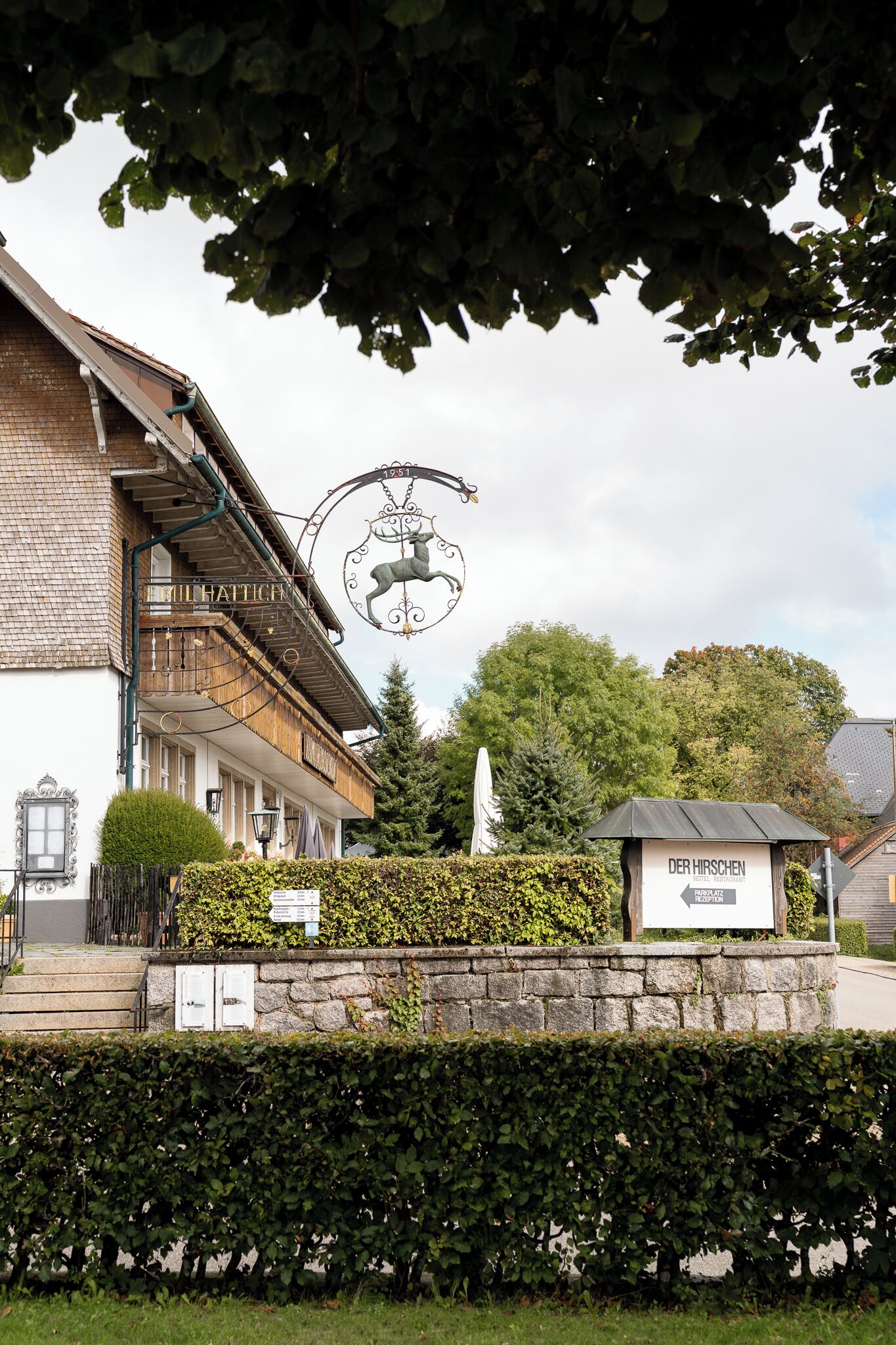 Un bâtiment avec une enseigne indiquant « DER HIRSCHEN » et un panneau indiquant « RÉCEPTION » devant l’entrée.