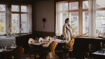 A dining area with a table set for a meal, a person standing by the window, and a view of the outside.