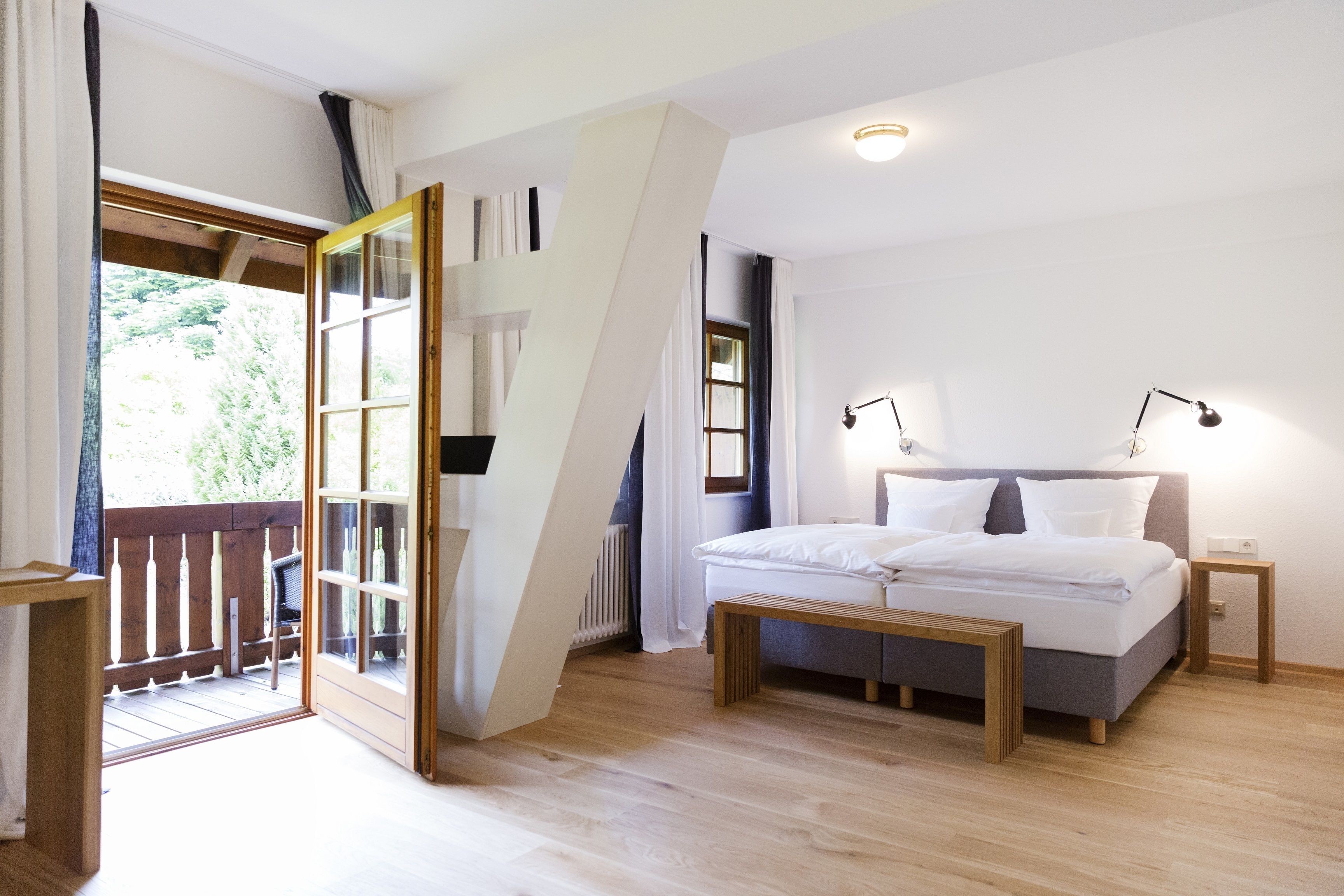 A bedroom with a bed, bedside tables, and a view of the outdoors.
