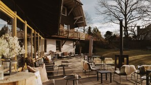 An outdoor patio with multiple seating areas, including chairs and tables, and a wooden deck.