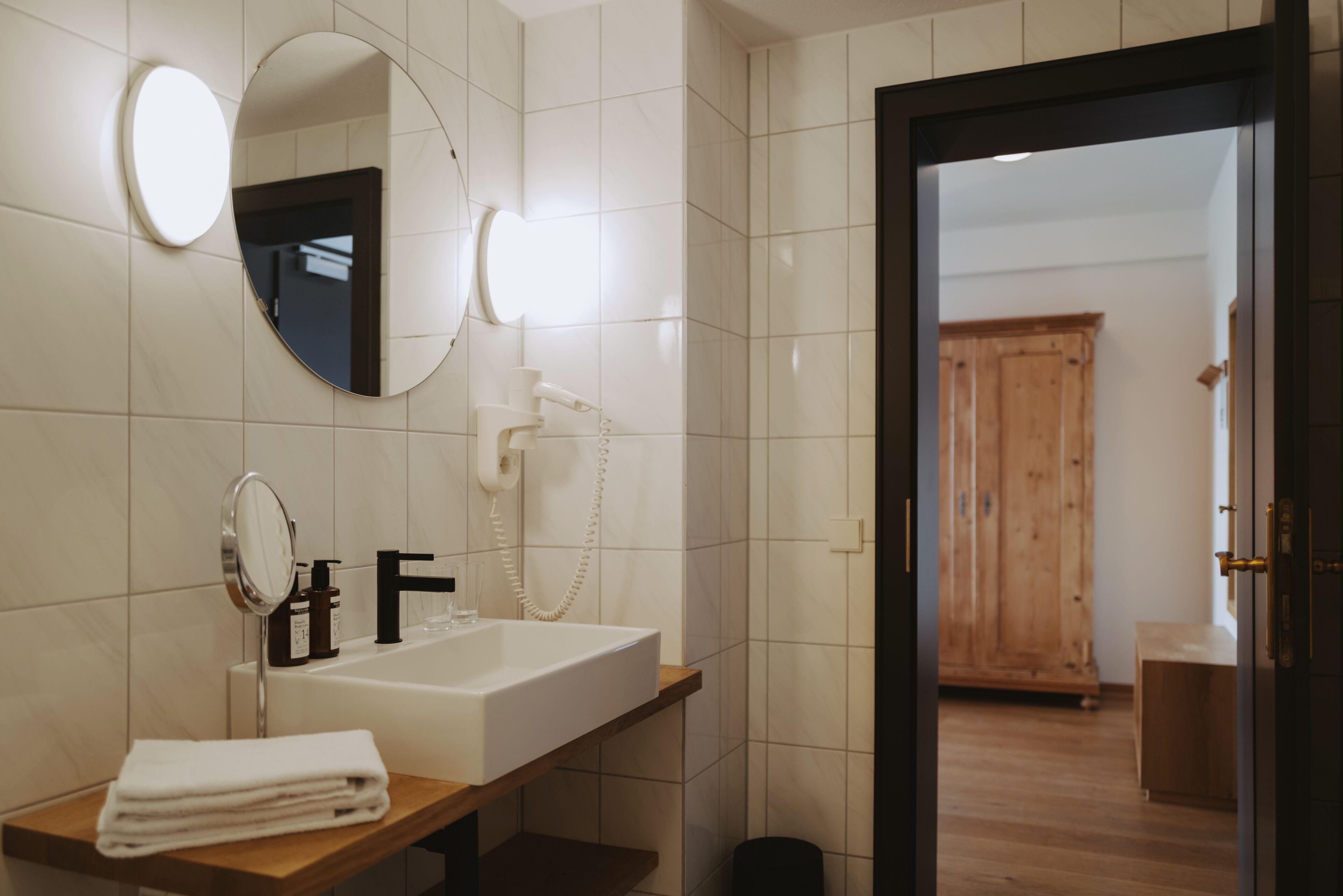 A bathroom with a white sink, a mirror, a towel, and a wooden cabinet.