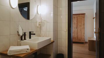 A bathroom with a white sink, a mirror, a towel, and a wooden cabinet.