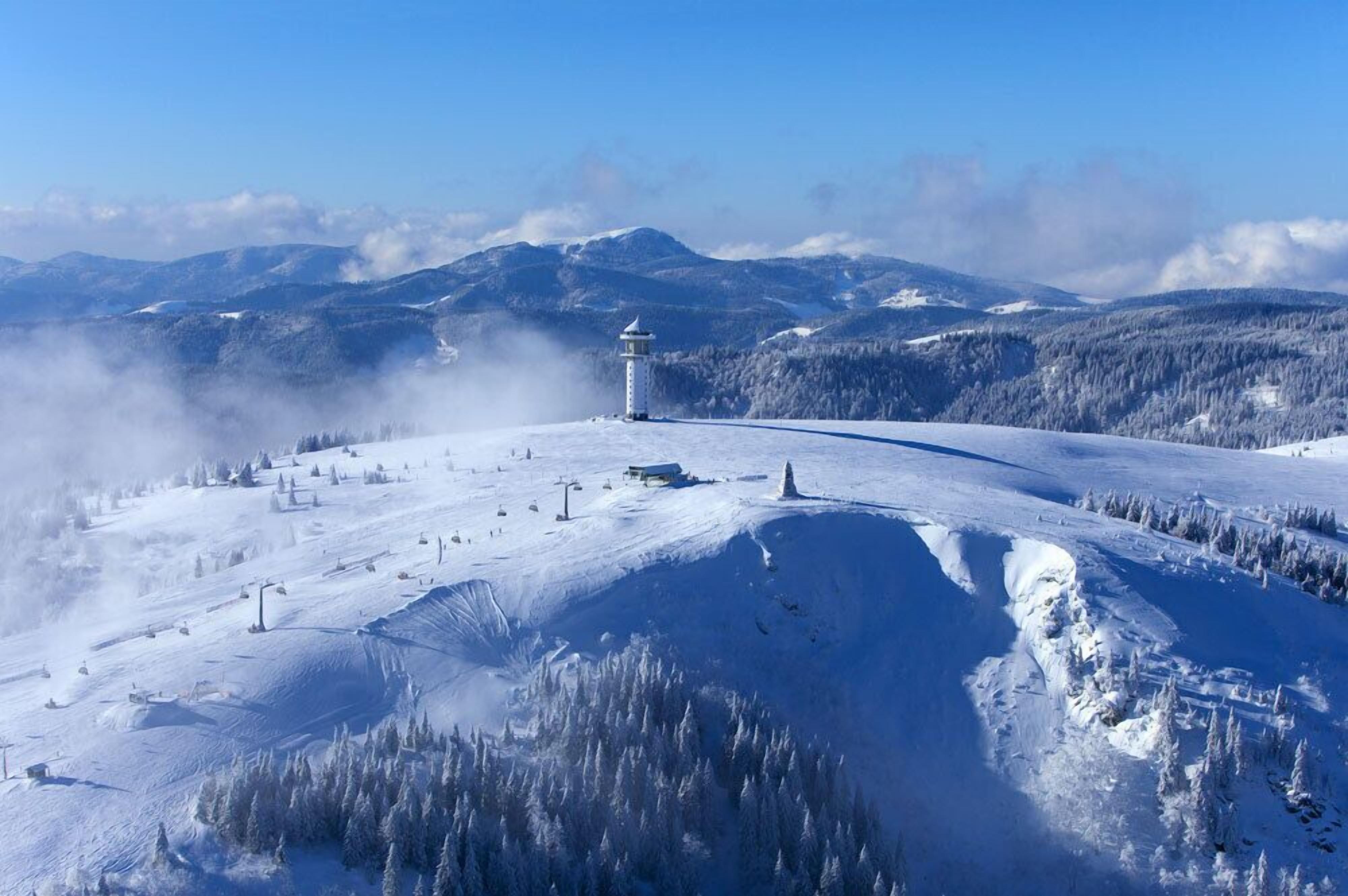 A snow-covered mountain landscape with a ski resort, including ski lifts and a lodge.
