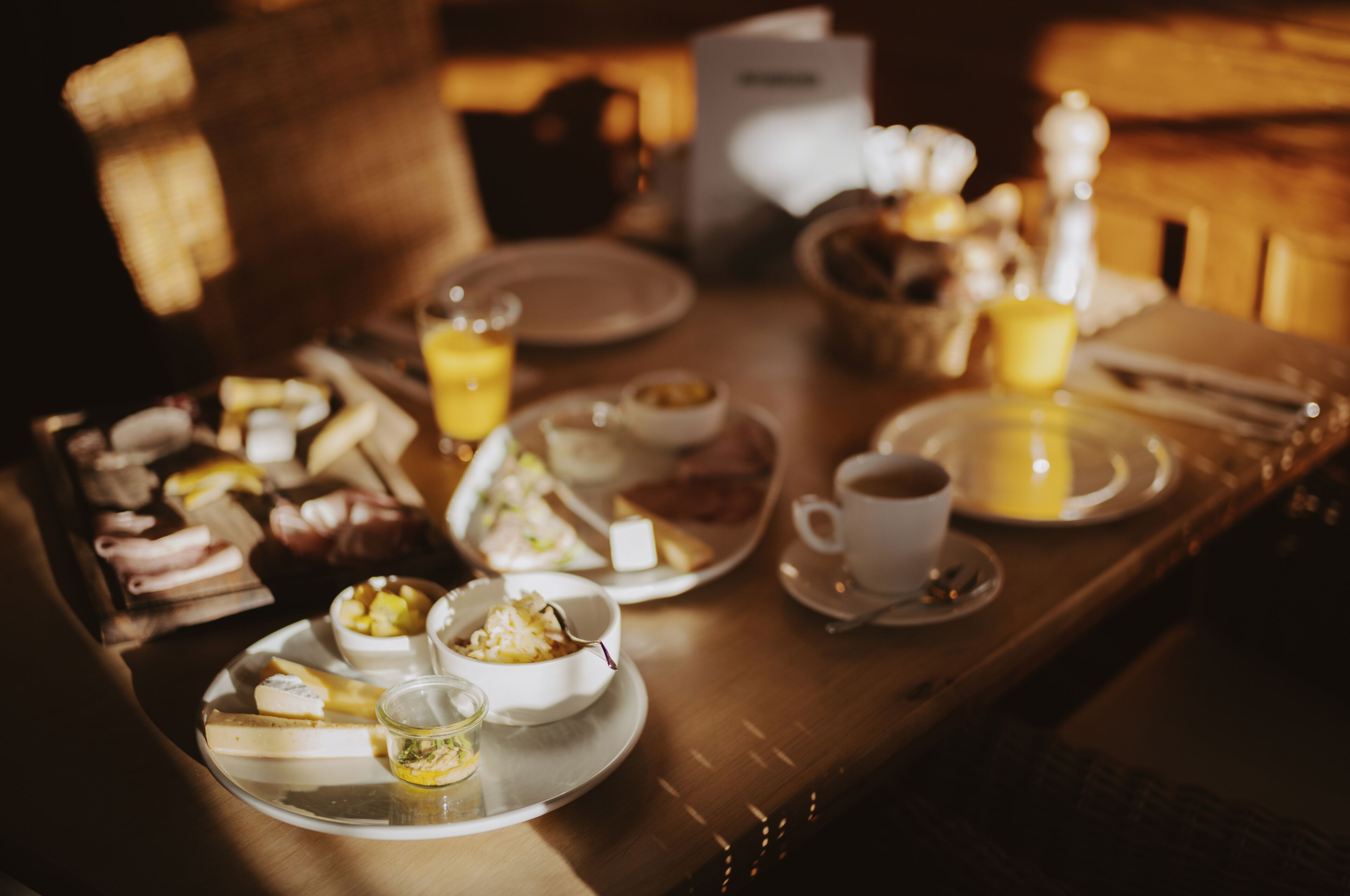 Una escena de desayuno con platos de comida, una taza de café y una vela sobre una mesa de madera.