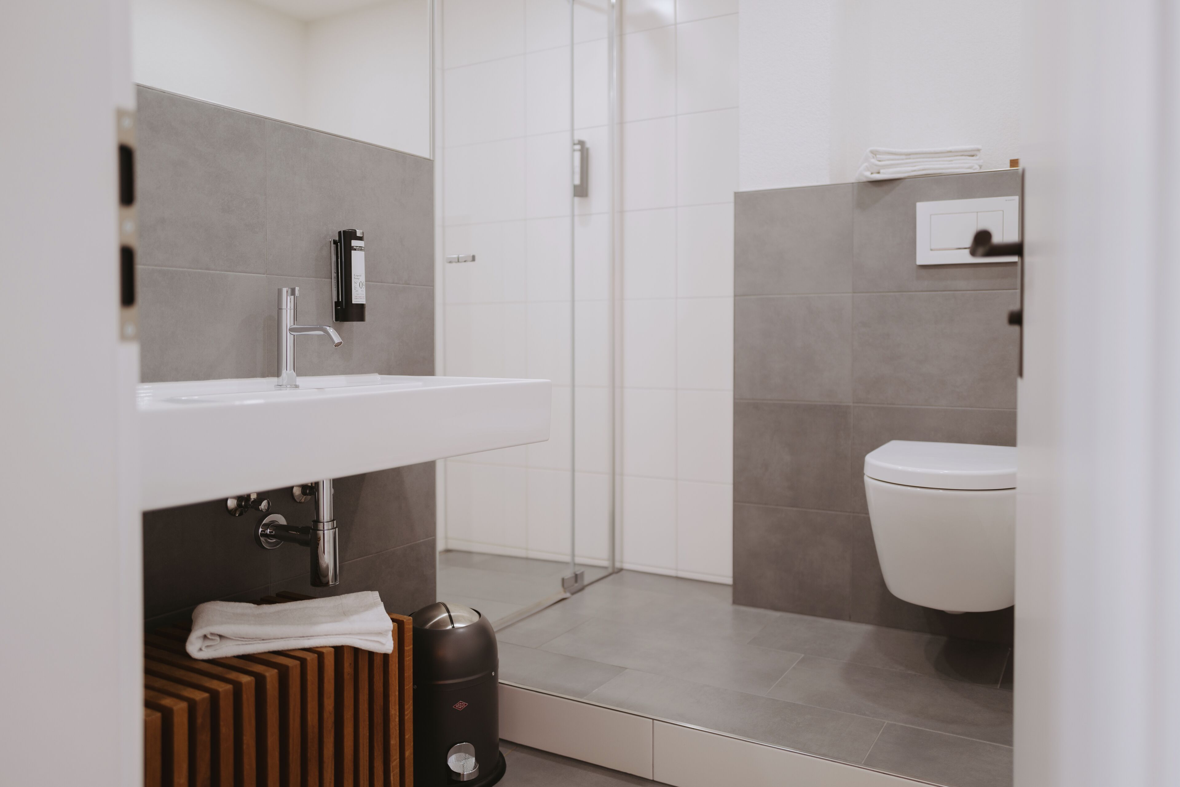 A modern bathroom with a white sink, a toilet, and a shower area.