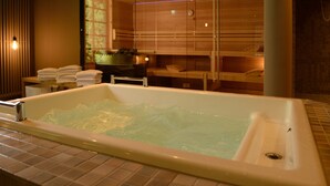 A modern bathroom with a large bathtub, a glass shower enclosure, and a wooden vanity with towels.