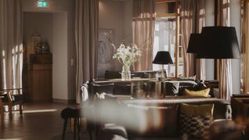 A hotel lobby with a sofa, chairs, a table with a vase, and a lamp.