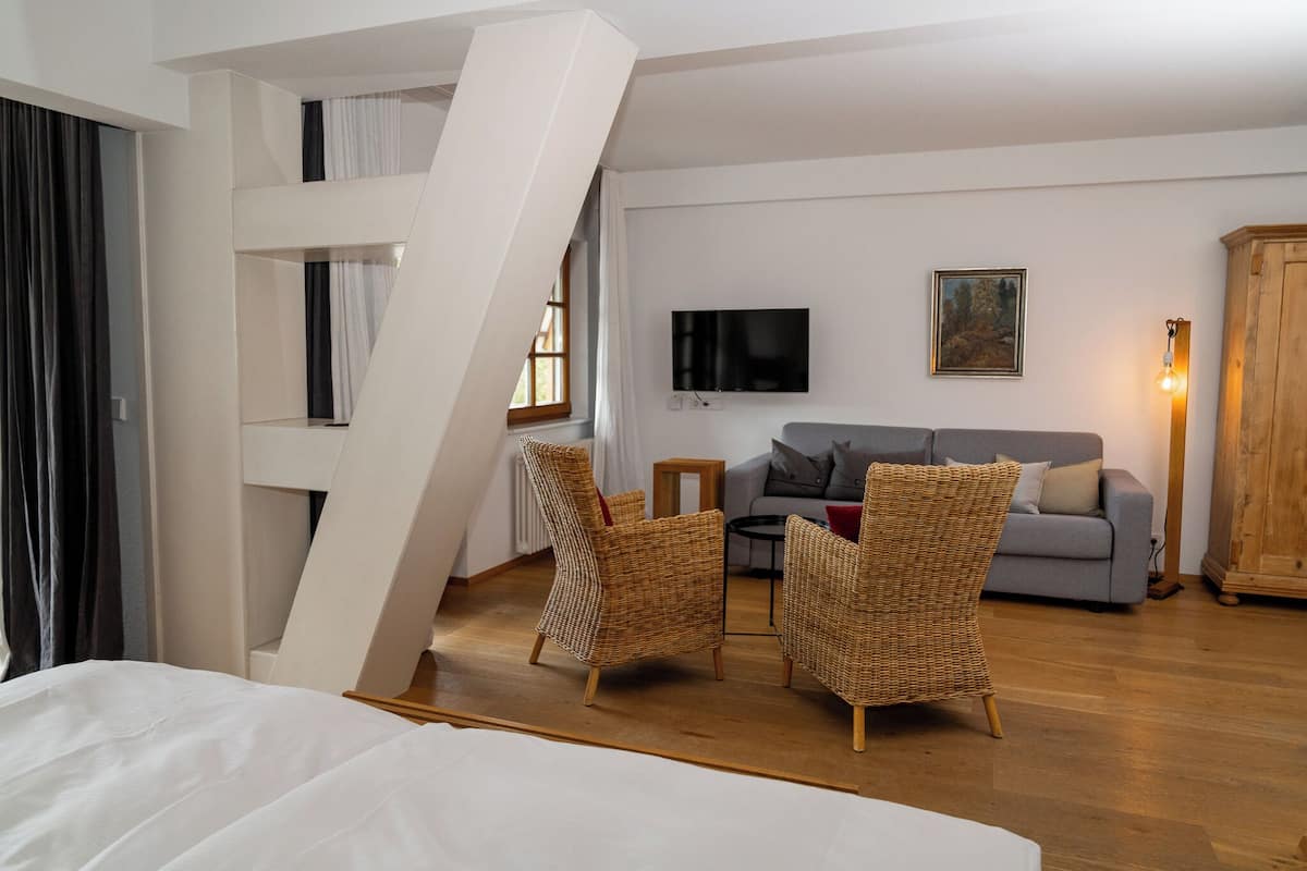 Una sala de estar moderna con un sofá gris, sillas de mimbre, un televisor de pantalla plana y un mueble de madera.