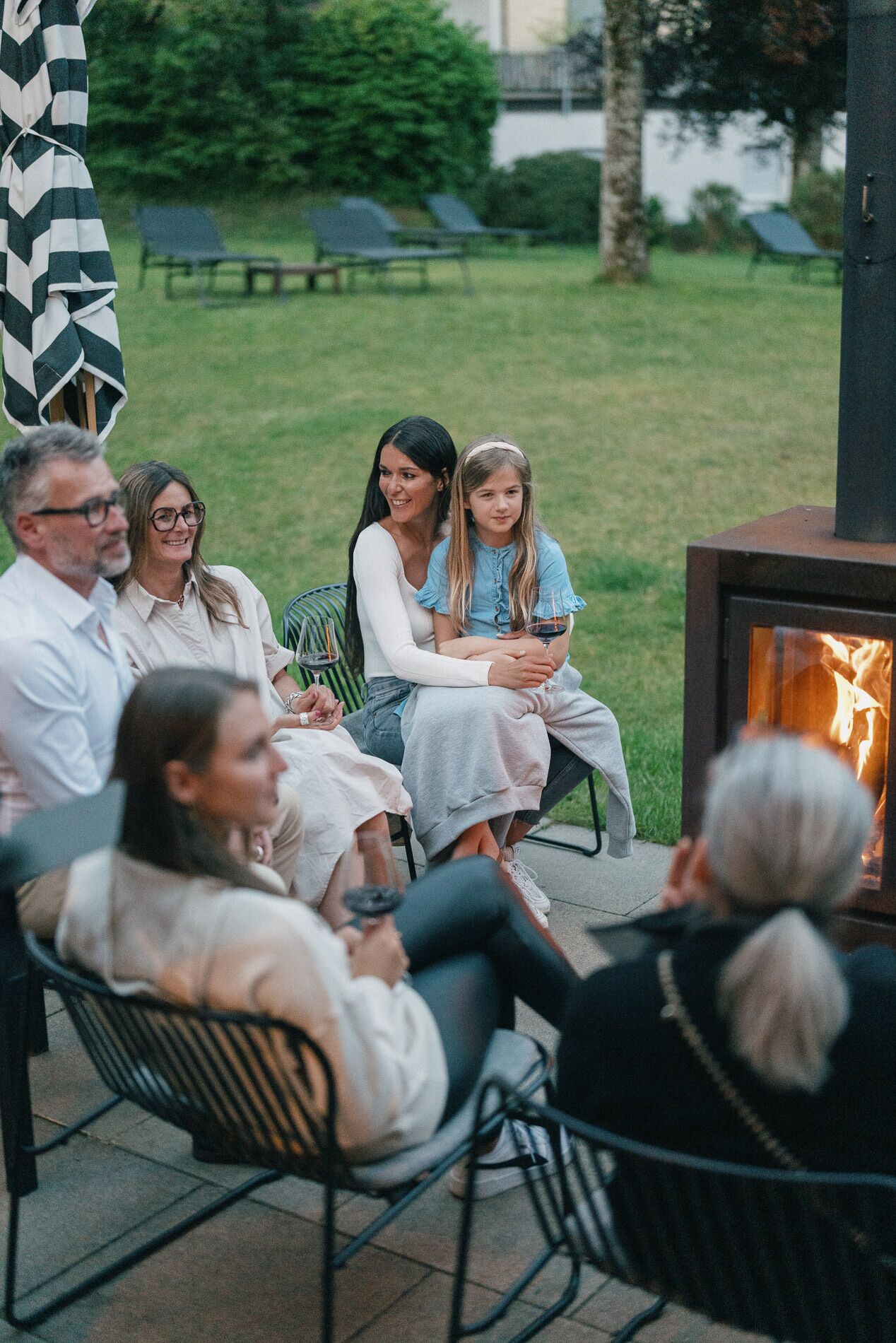 A group of people seated around a fire pit in an outdoor setting.