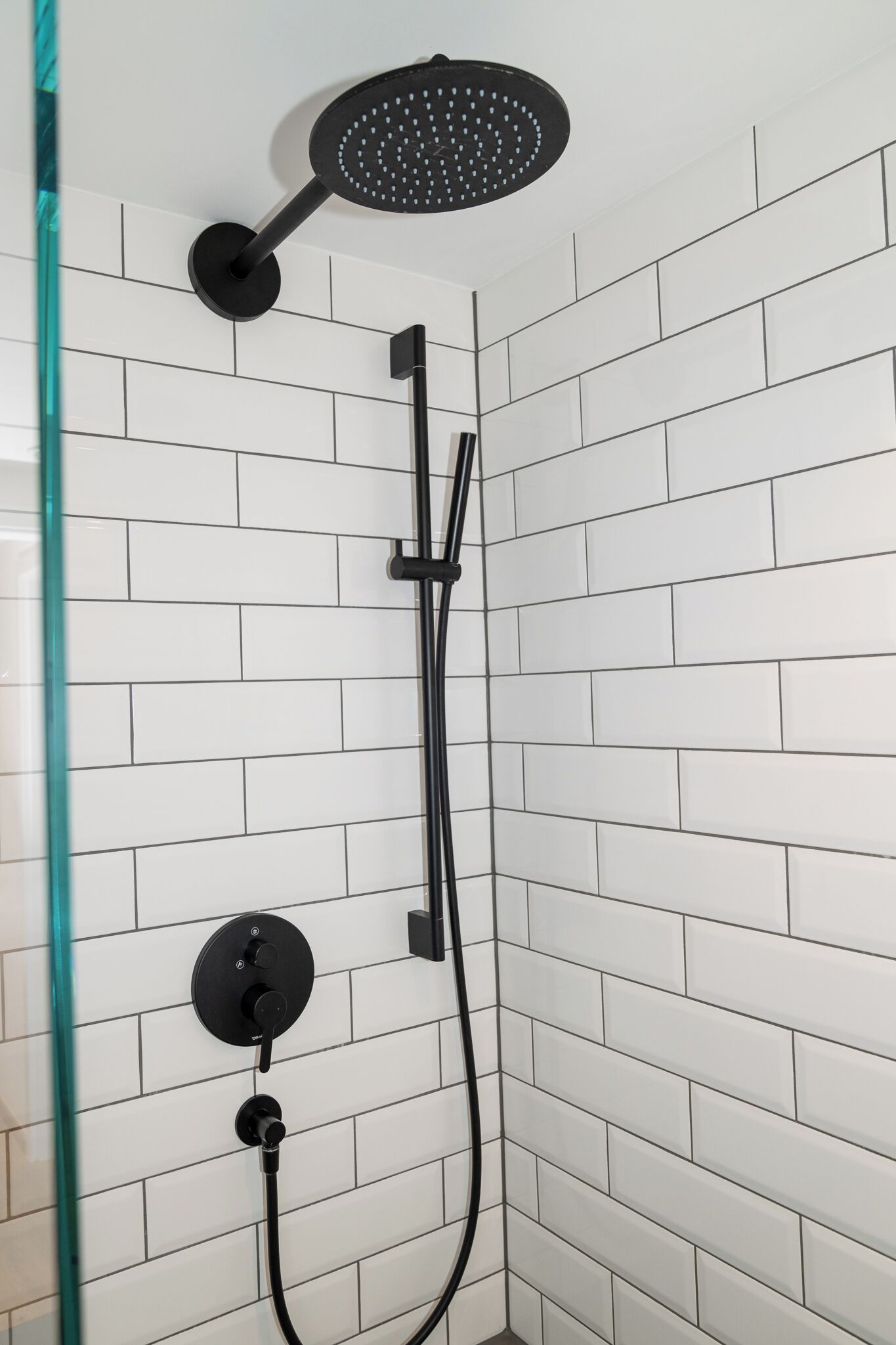 Une douche moderne dotée d’un pommeau de douche à main et d’un panneau de commande fixé au mur.
