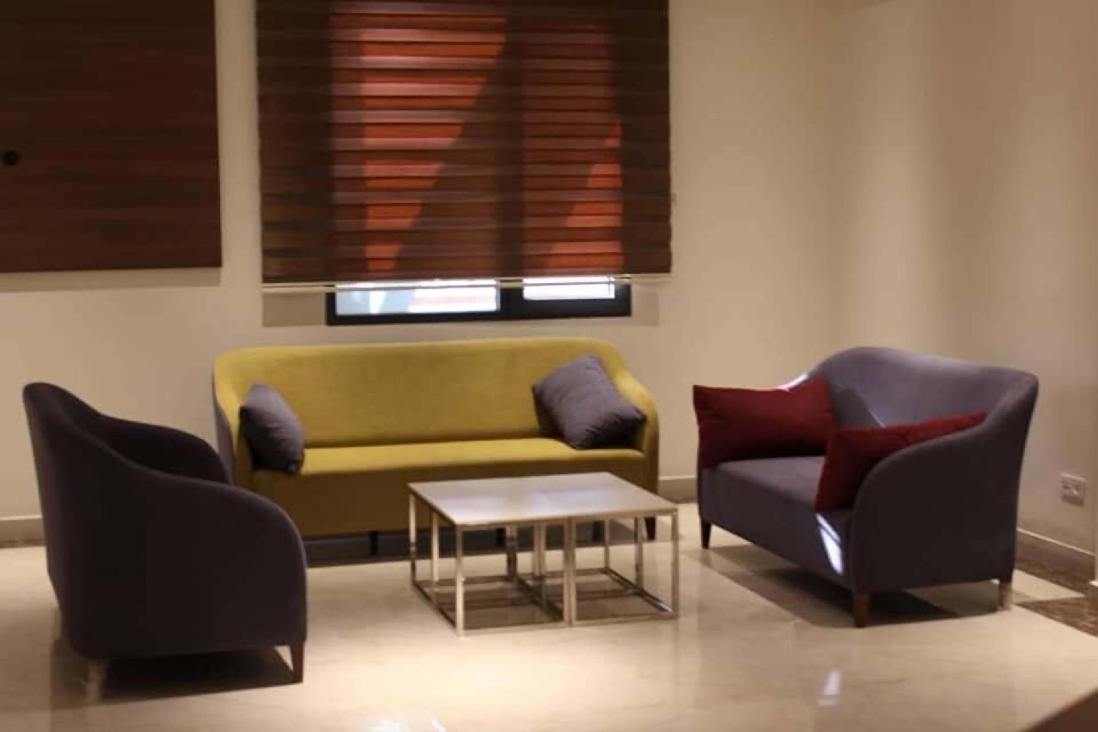 A living room with a yellow sofa, a dark armchair, and a small table.