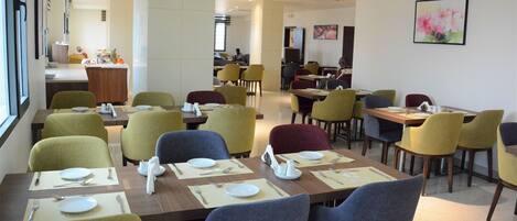 A restaurant with multiple tables and chairs, some with plates and cutlery.