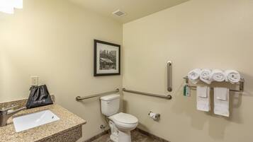 A bathroom with a sink, toilet, hand dryer, and towel rack.