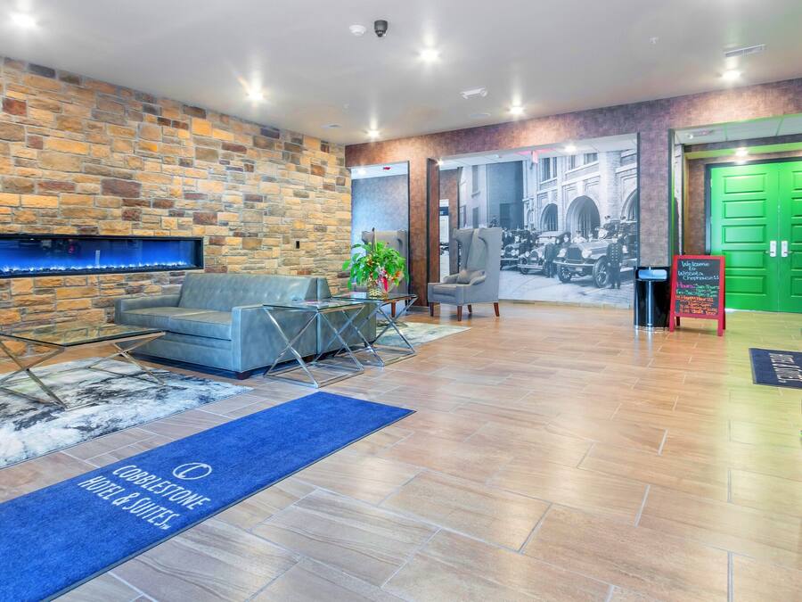 Un hall de hotel con una pared de piedra, un sofá, una mesa de centro, una recepción y una puerta verde.