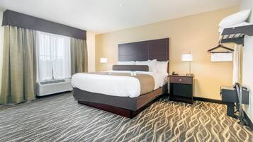 Quarto de hotel com uma cama grande, mesas de cabeceira, aquecedor, abajur e cabideiro.