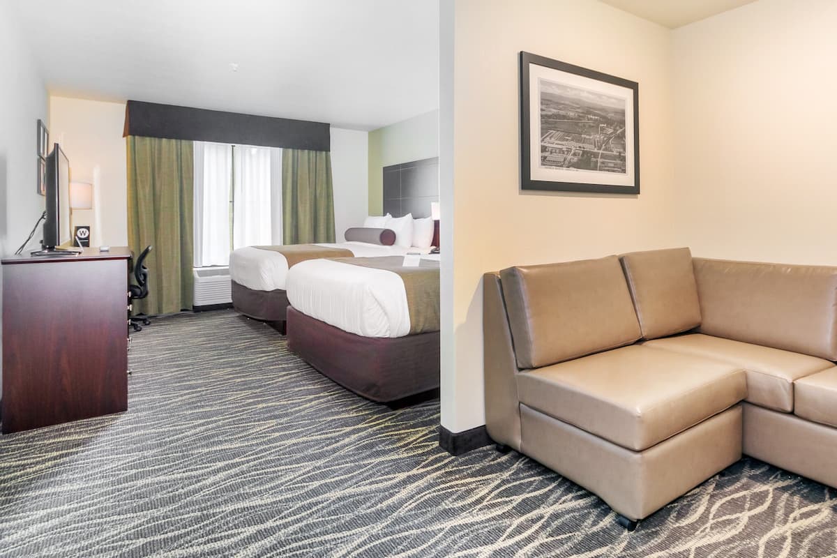 Ein Hotelzimmer mit einem großen Bett, einem Sofa, einem Schreibtisch und einem gerahmten Bild an der Wand.