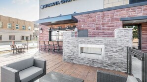 An outdoor patio area with a stone wall, seating, and a grill. - Cobblestone Hotel and Suites Janesville (Janesville)