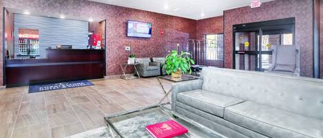 Un vestíbulo de hotel con mostrador de recepción, zona de estar y un ventanal grande.