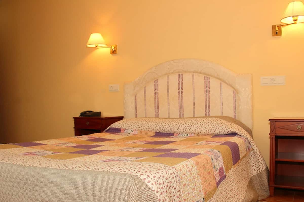Een slaapkamer met een bed, nachtkastje en een houten kast.