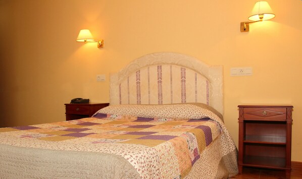 Un dormitorio con cama, mesita de noche y aparador de madera.