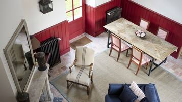 A dining area with a wooden table, red paneled walls, and a blue sofa.