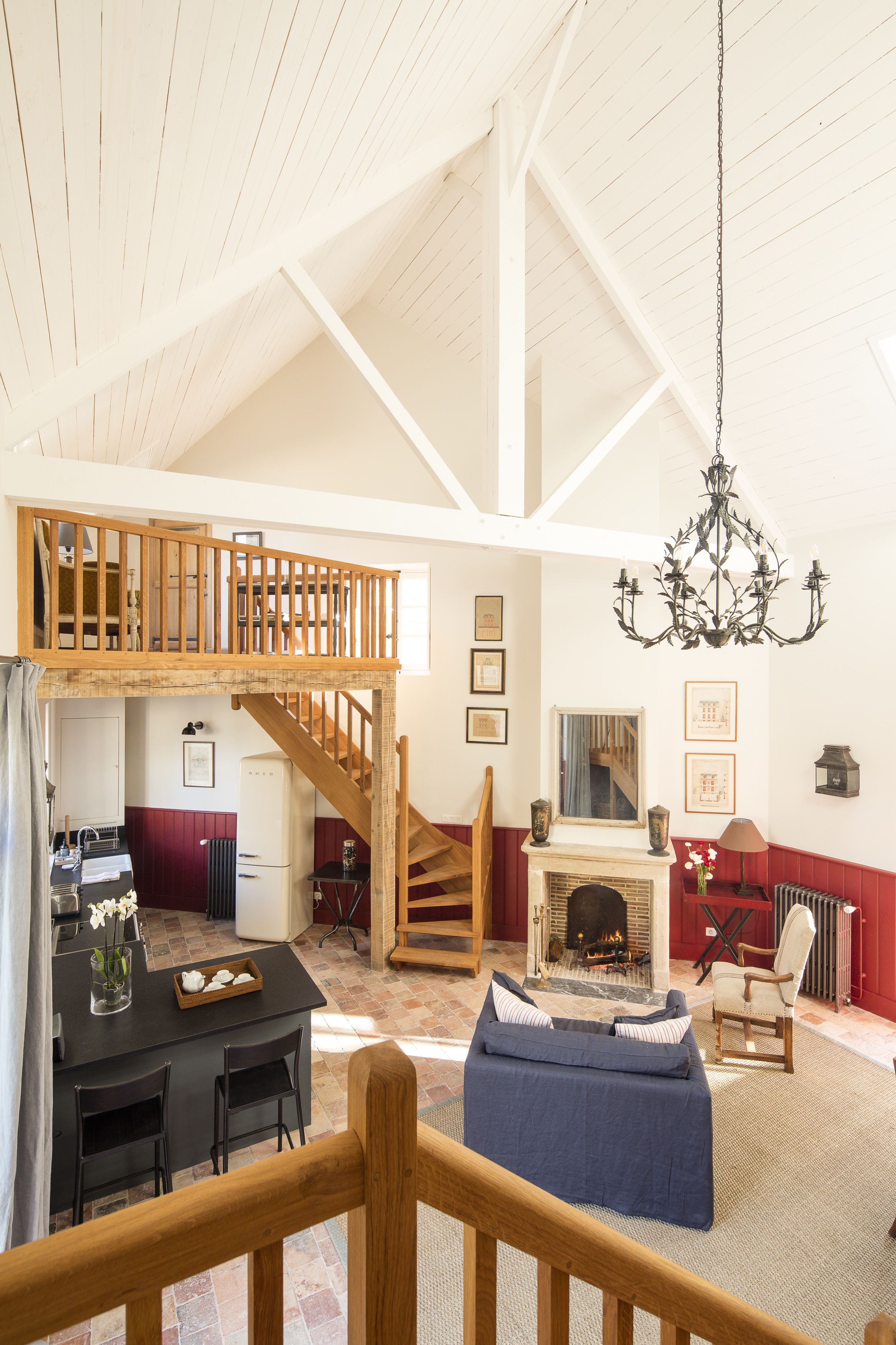 Un loft espacioso con techo alto, una escalera de madera, una chimenea y un comedor con mesa y sillas.