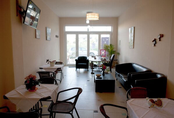 A spacious living area with a sofa, chairs, a coffee table, and a dining table with a potted plant.