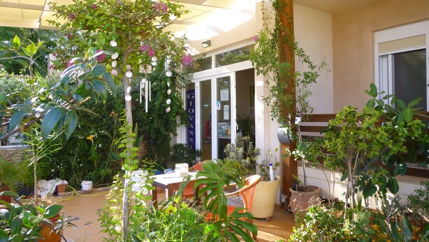 A covered patio area with potted plants, a table, and chairs. - Giovanni Mare (Ilida)