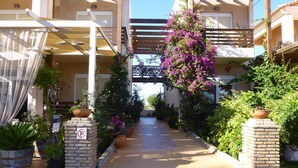 A covered walkway with potted plants and a no parking sign. - Giovanni Mare (Ilida)