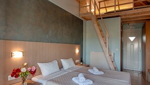 A bedroom with a large bed, wooden ceiling beams, a nightstand with a vase of flowers, and a staircase leading to another room. - Giovanni Mare (Ilida)