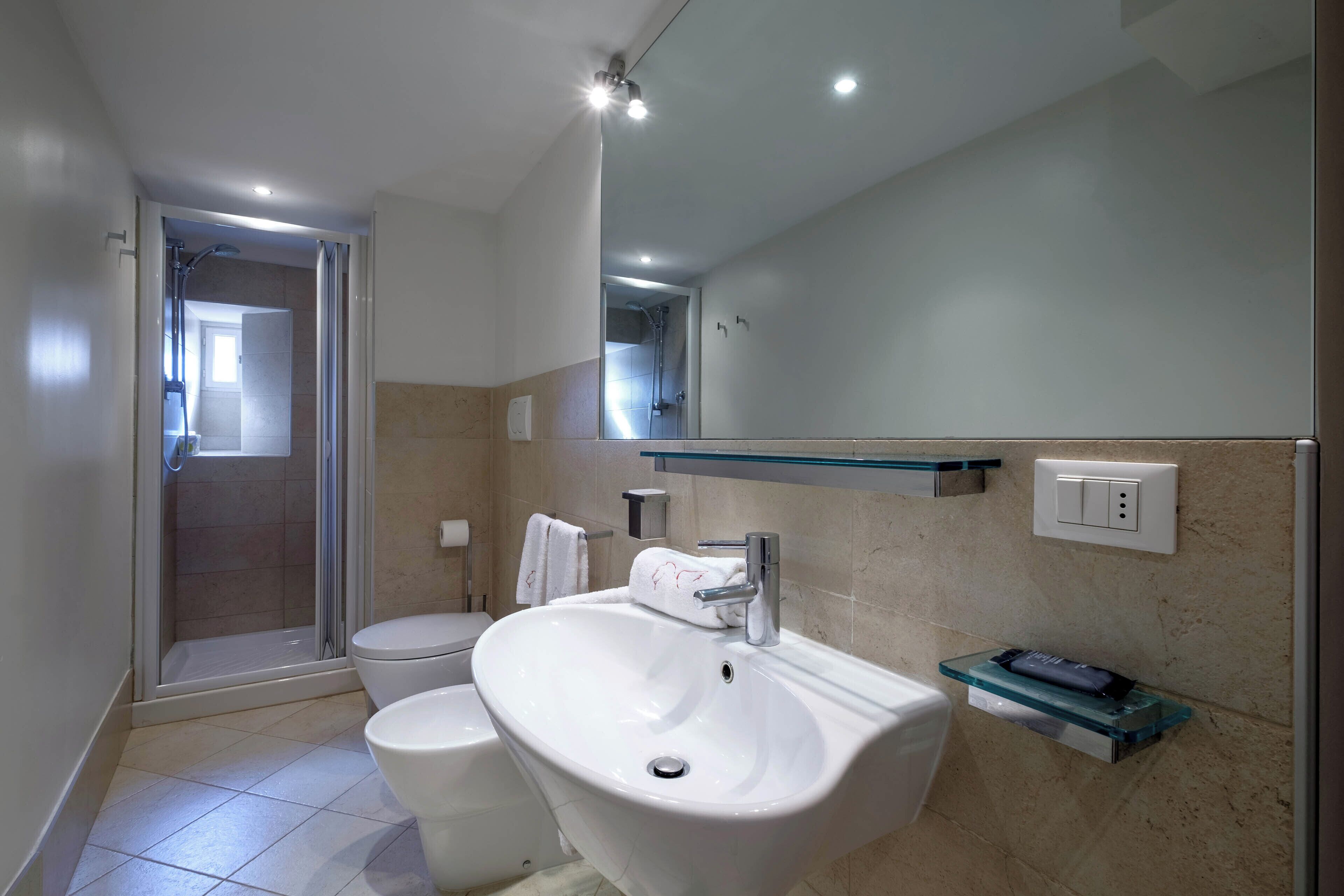 Een moderne badkamer met een douchecabine van glas, een witte wastafel en een toilet.