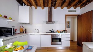 A modern kitchen with white cabinetry, a stainless steel oven, and a wooden ceiling. - The Lion House (Venice)
