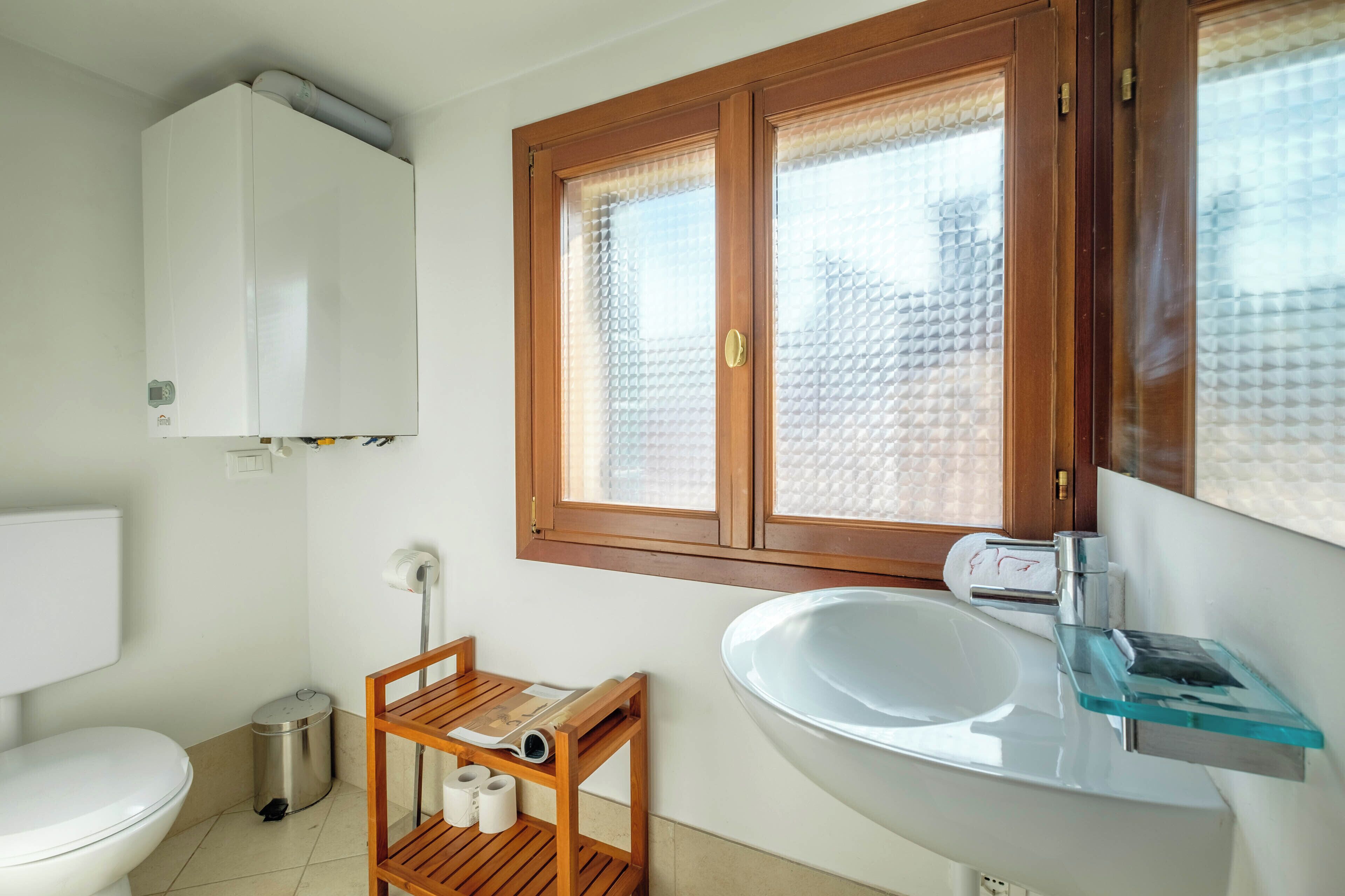 A bathroom with a toilet, sink, and window.