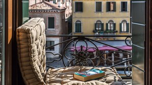 Un balcon doté d’un espace salon avec des coussins, d’un livre et offrant une vue sur les bâtiments.