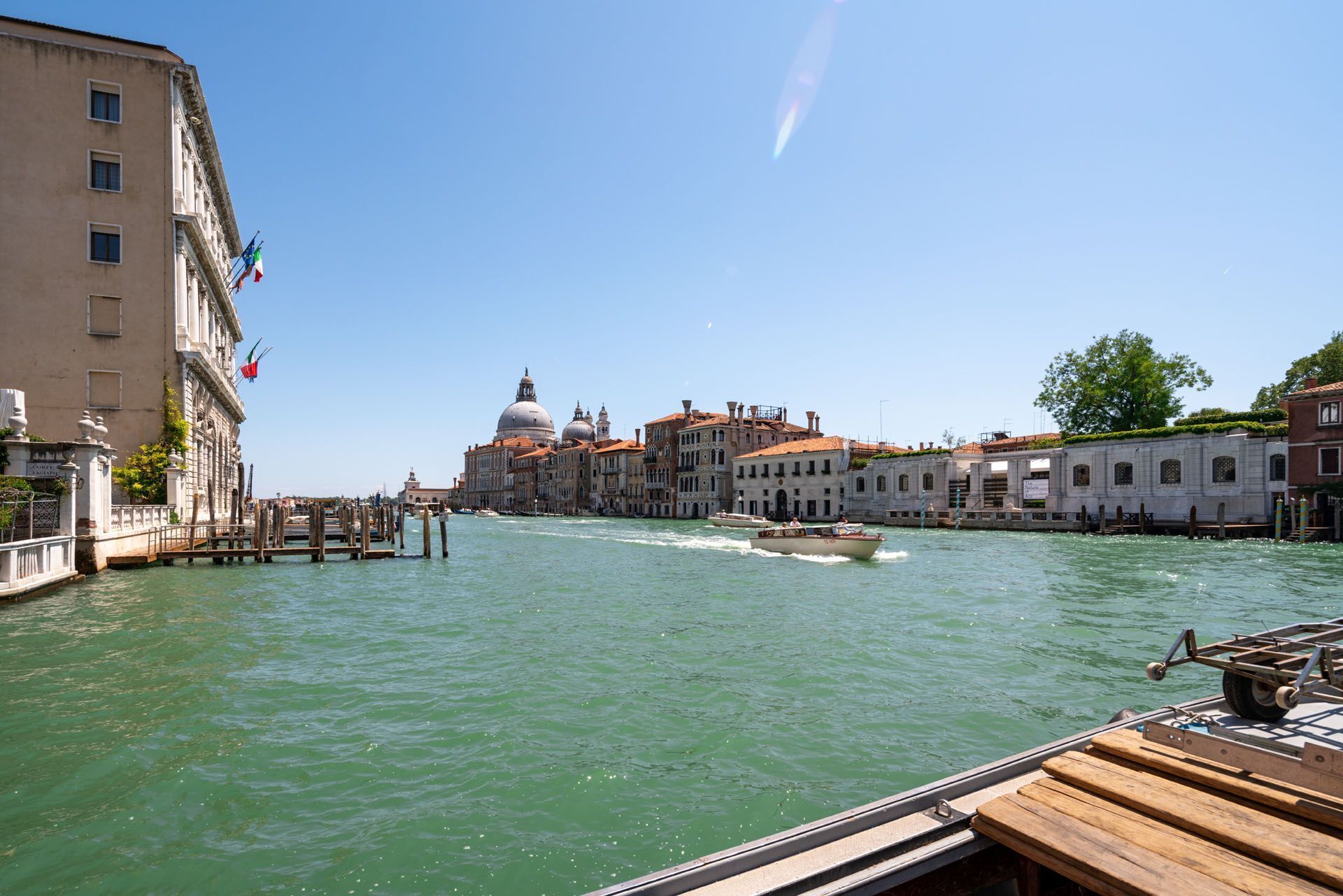 A canal with boats, historic buildings, and a prominent dome structure.