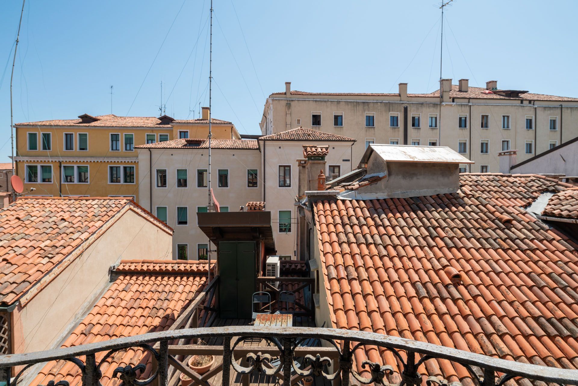 Vista de tejados de tejas color terracota y edificios con balcones, mostrando una mezcla de estilos arquitectónicos.