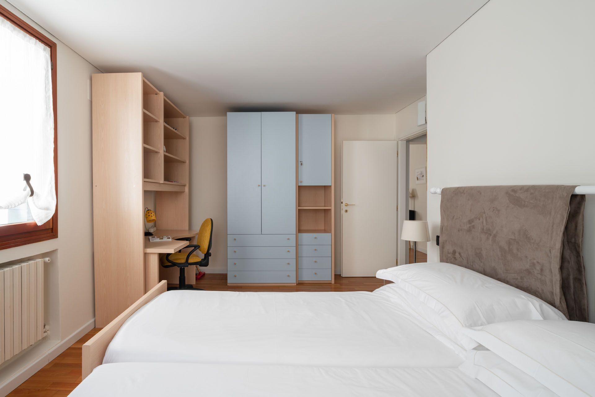 A bedroom with a bed, a desk, and a wardrobe.