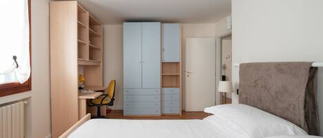 A bedroom with a bed, a desk, and a wardrobe.