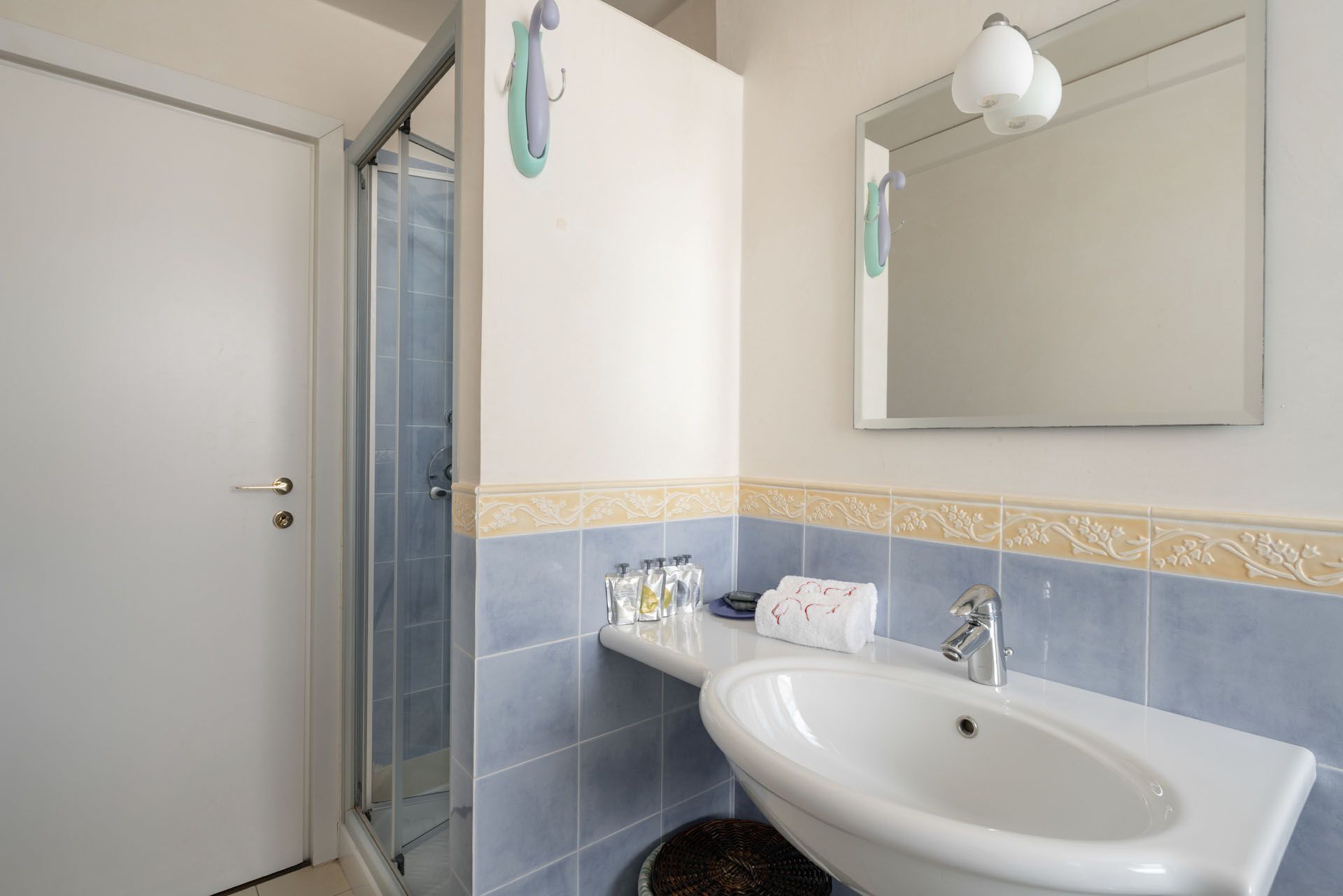 A bathroom with a white sink, a mirror, and a shower with a glass door.