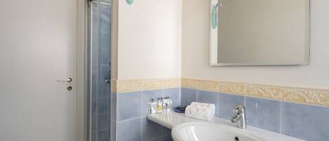 A bathroom with a white sink, a mirror, and a shower with a glass door.