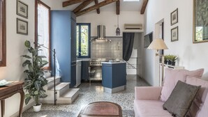 A compact kitchen with blue cabinets, a built-in oven, and a hanging light fixture. - Three Terraces (Venice)